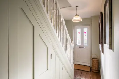 a hallway with white stairs and a door at 7 Highbury Cottages, Leiston in Leiston