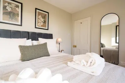 a bedroom with a white bed with a mirror at 7 Highbury Cottages, Leiston in Leiston