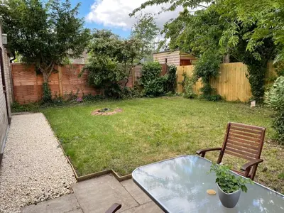 a patio with a glass table and a chair in a yard at Stylish 3BR Cambridge Bungalow, Near Science Park in Cambridge