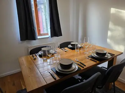 a wooden table with plates and wine glasses on it at Stylish 3BR Cambridge Bungalow, Near Science Park in Cambridge