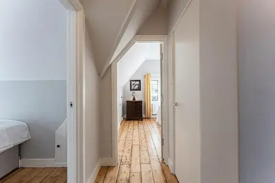 a hallway with a bed and a wooden floor at Idyllic, Private and Picturesque Cottage in Newmarket