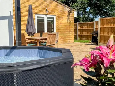 a hot tub in a yard with a table and a umbrella at A12 & A14 Location - Suffolk IP3 - Secure Parking x3 in Nacton