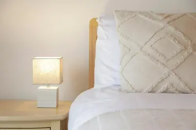 a bed with a white pillow and a table with a lamp at A12 & A14 Location - Suffolk IP3 - Secure Parking x3 in Nacton