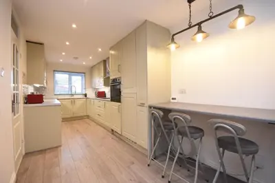 a kitchen with white cabinets and bar stools at Ideal Contractor & Family Stay-Basildon Smart tv in Nevendon