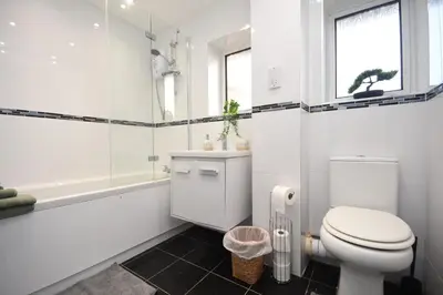 a white bathroom with a toilet and a bath tub at Ideal Contractor & Family Stay-Basildon Smart tv in Nevendon