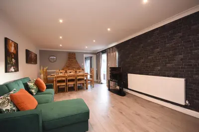 a living room with a green couch and a brick wall at Ideal Contractor & Family Stay-Basildon Smart tv in Nevendon