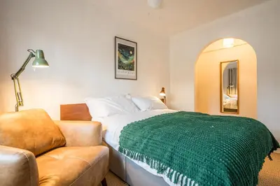 a bedroom with a bed with a green blanket on it at Flat Two, High Street in Saxmundham