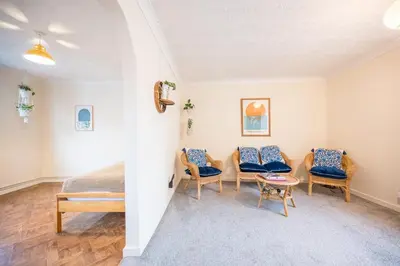 a bedroom with a bed and two chairs and a table at Flat Two, High Street in Saxmundham