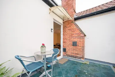 a patio with a table and chairs and a brick wall at Flat Two, High Street in Saxmundham
