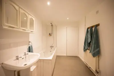 a white bathroom with a sink and a bath tub at Flat Two, High Street in Saxmundham