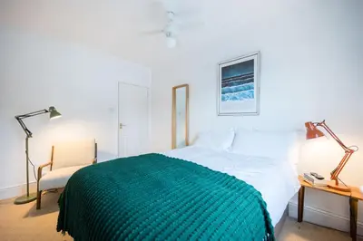 a bedroom with a bed and a chair and a lamp at Flat Two, High Street in Saxmundham