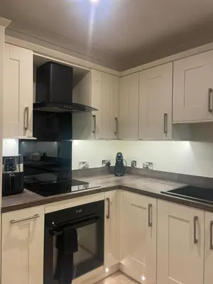 a kitchen with white cabinets and a black oven at The Waldegraves Hideaway in Bures Saint Mary