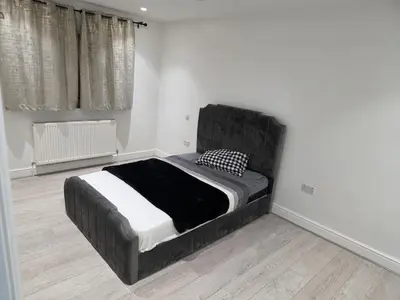a bedroom with a large bed in a room at Optimal Homes in Harold Wood