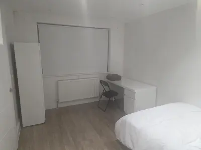 a bedroom with a bed and a desk with a chair at Optimal Homes in Harold Wood