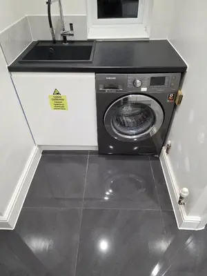 a washing machine in a kitchen with a sink at Optimal Homes in Harold Wood