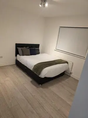 a bedroom with a bed with a whiteboard on the wall at Optimal Homes in Harold Wood