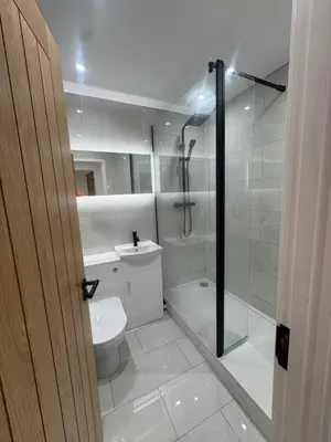 a white bathroom with a shower and a toilet at Olivers retreat in Braintree