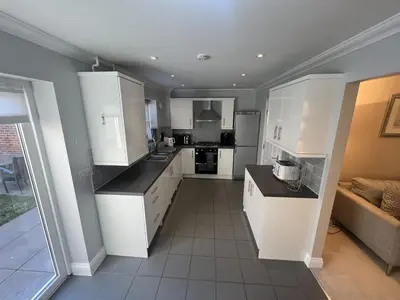 a kitchen with white cabinets and a tile floor at Siskin House in Wickham Market