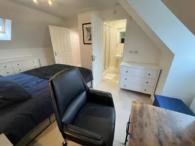 a bedroom with a bed and a chair and a table at Siskin House in Wickham Market