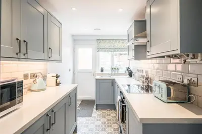 a kitchen with white cabinets and a sink at 1 Lavender Cottages, Knodishall in Saxmundham