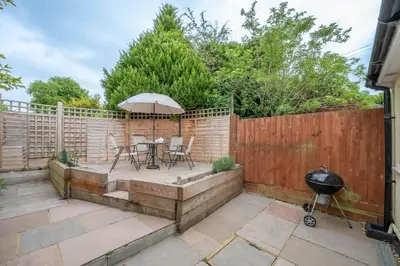 a patio with a table and an umbrella at 1 Lavender Cottages, Knodishall in Saxmundham