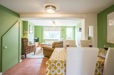a living room with green walls and a dining room at 1 Lavender Cottages, Knodishall in Saxmundham