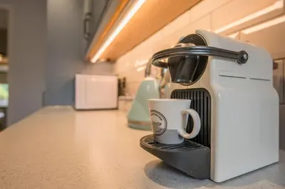 a coffee maker with a cup on a counter at 1 Lavender Cottages, Knodishall in Saxmundham