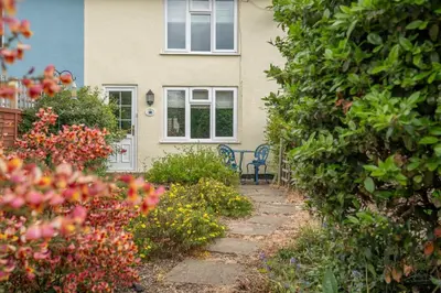 a house with a bench in front of a garden at 1 Lavender Cottages, Knodishall in Saxmundham