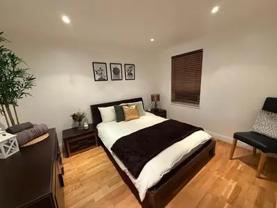 a bedroom with a large bed and a chair at Large 5BR House with FREE Parking and WiFi plus Garden in Basildon, Essex in Basildon