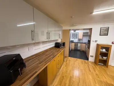 a kitchen with white cabinets and a wooden counter top at Large 5BR House with FREE Parking and WiFi plus Garden in Basildon, Essex in Basildon