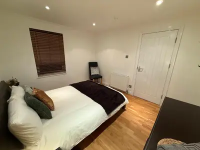 a bedroom with a bed with white sheets and pillows at Large 5BR House with FREE Parking and WiFi plus Garden in Basildon, Essex in Basildon