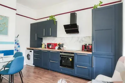 a kitchen with blue cabinets and blue chairs at 1BR Super King sized Apartment Contractor friendly - Free Parking! in Southend-on-Sea