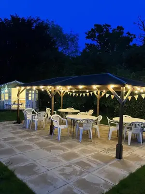 a group of tables and chairs under a pavilion with lights at Grange Farm in Thetford
