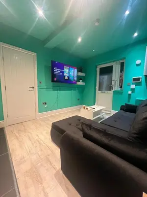 a living room with a couch and a flat screen tv at The Emerald Aura Stay By Cambridge Central Station in Cambridge