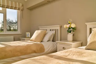 a bedroom with two beds and a vase of flowers at Finest Retreats - Heron Luxury Lodge