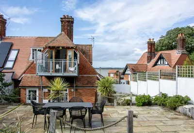 a house with a table and chairs in front of it at 1 Quay Cottage in Bawdsey