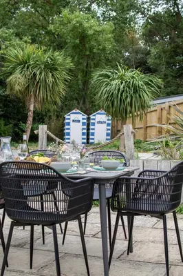 a table with three chairs and a table with dishes on it at 1 Quay Cottage in Bawdsey