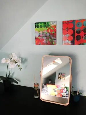 a mirror on a table in a room with paintings at 'The Artist's Loft' - Studio Flat in Cambridge in Cambridge