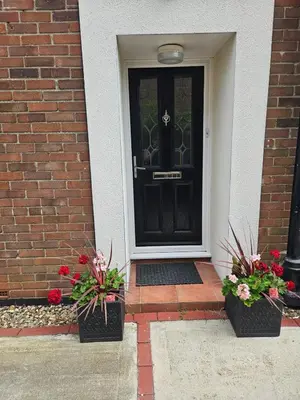 a black door with two potted plants in front of it at Bungalow with a view in Kirby Cross