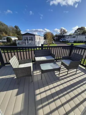 a patio with a table and chairs on a deck at Lovely Caravan With Front Decking At Carlton Meres Park Ref 60018R in Saxmundham
