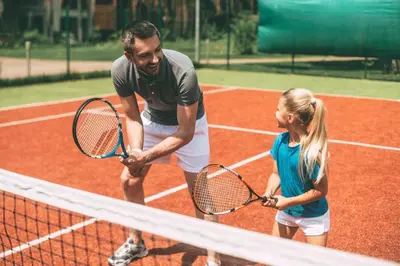a man and a girl holding tennis rackets on a tennis court at Lovely Caravan With Front Decking At Carlton Meres Park Ref 60018R in Saxmundham