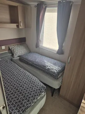two beds in a small room with a window at Lovely Caravan With Front Decking At Carlton Meres Park Ref 60018R in Saxmundham