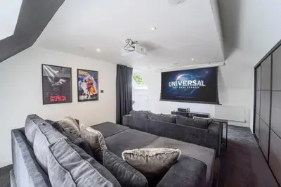 a living room with a couch and a tv at Emerson Park Villa, Heated Pool, Hot Tub, Cinema in Harold Wood