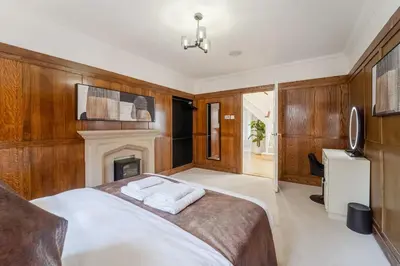 a bedroom with a large bed and a fireplace at Emerson Park Villa, Heated Pool, Hot Tub, Cinema in Harold Wood