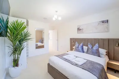 a bedroom with a large bed with blue pillows at Emerson Park Villa, Heated Pool, Hot Tub, Cinema in Harold Wood