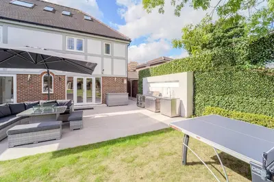a backyard with a ping pong table in front of a house at Emerson Park Villa, Heated Pool, Hot Tub, Cinema in Harold Wood