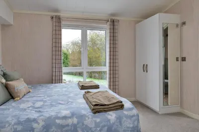 a bedroom with a bed and a large window at Finest Retreats - Churchill Luxury Lodge