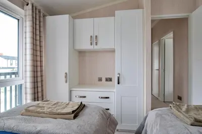 a bedroom with white cabinets and a bed and a window at Finest Retreats - Churchill Luxury Lodge