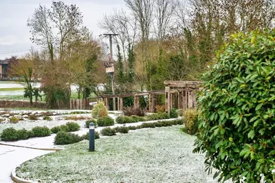 a garden with snow on the grass and a fence at Finest Retreats - Churchill Luxury Lodge
