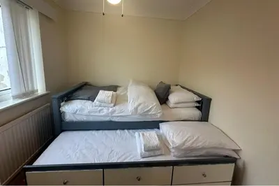 two beds in a small room with a window at 4 Bed House - Sleeps 8 - Pets - Parking - Wifi in Great Clacton